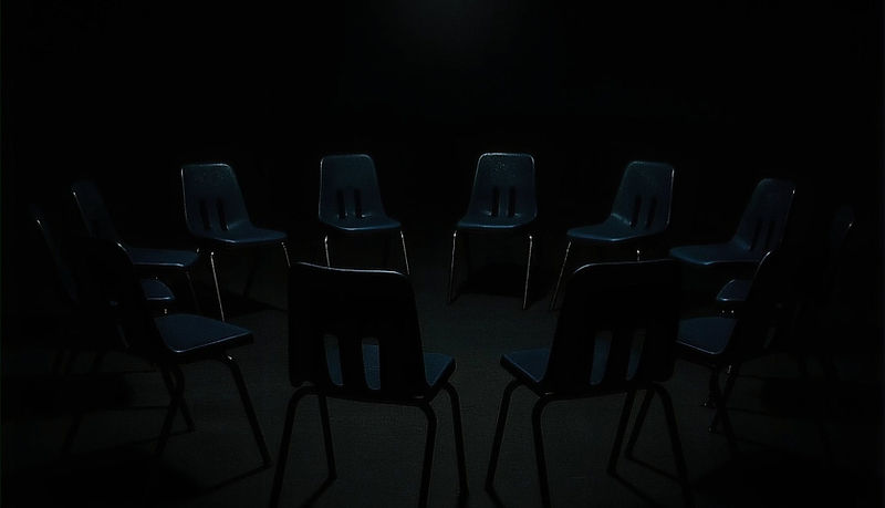 A circle of empty chairs under a single overhead light