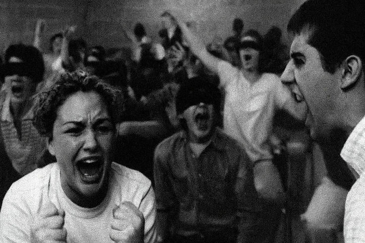 A black-and-white group photograph: a young person screaming with clenched fists, another yelling, a third with eyes covered
