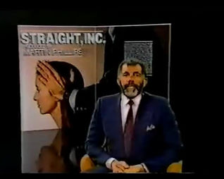 A studio interview: a man in a suit at a desk beside a panel lettered Straight, Inc. — The Alternative.