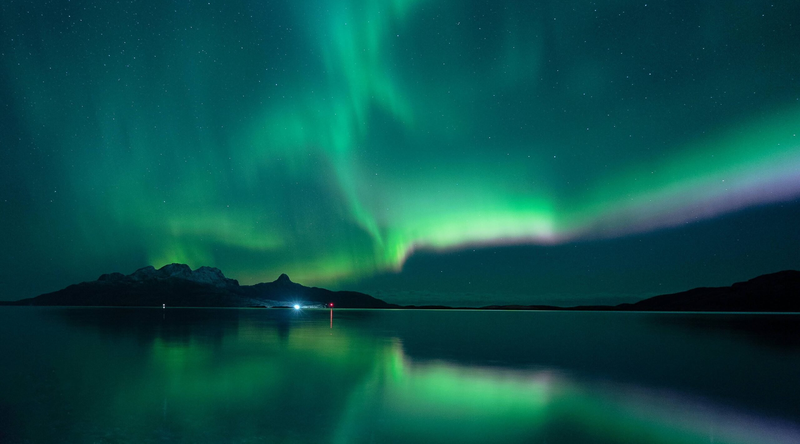 Norrsken i grönt över stilla fjällsjö i svenska Lappland
