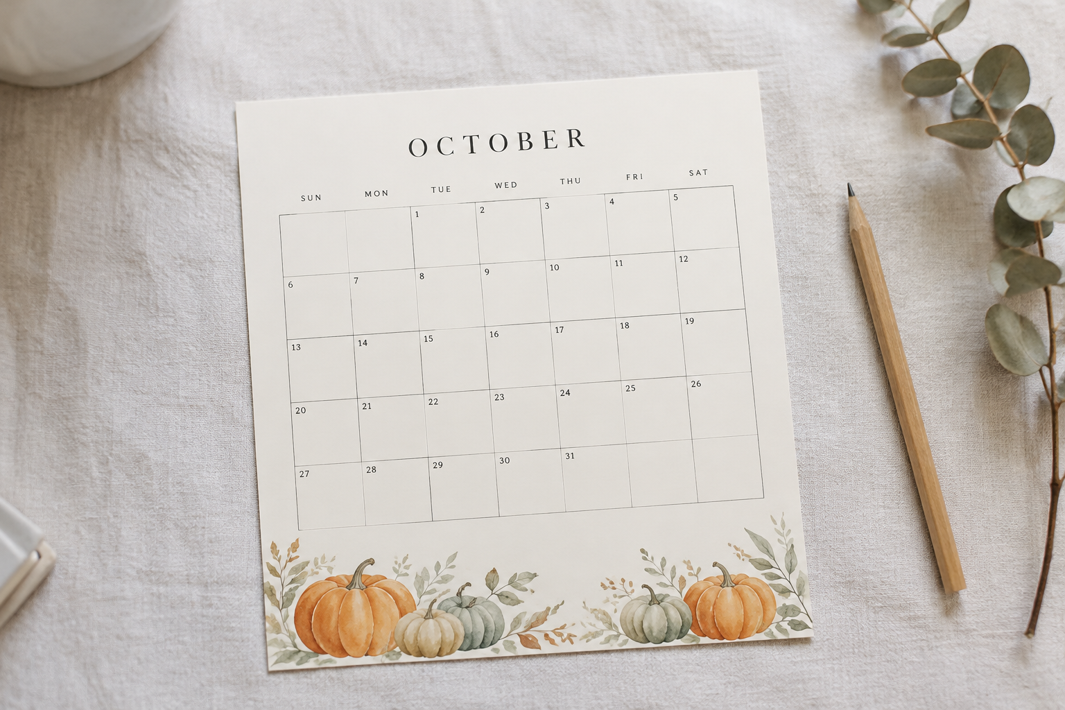 Minimal watercolour printable October calendar on cream paper with soft orange pumpkins along the bottom edge
