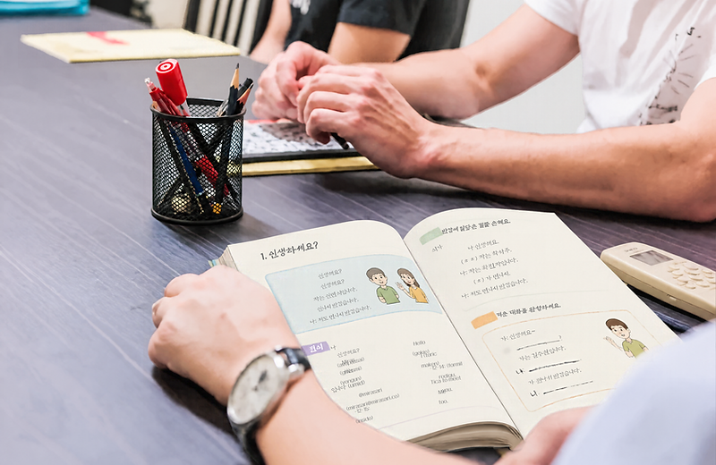 An open Active Korean textbook and study notes on a classroom table
