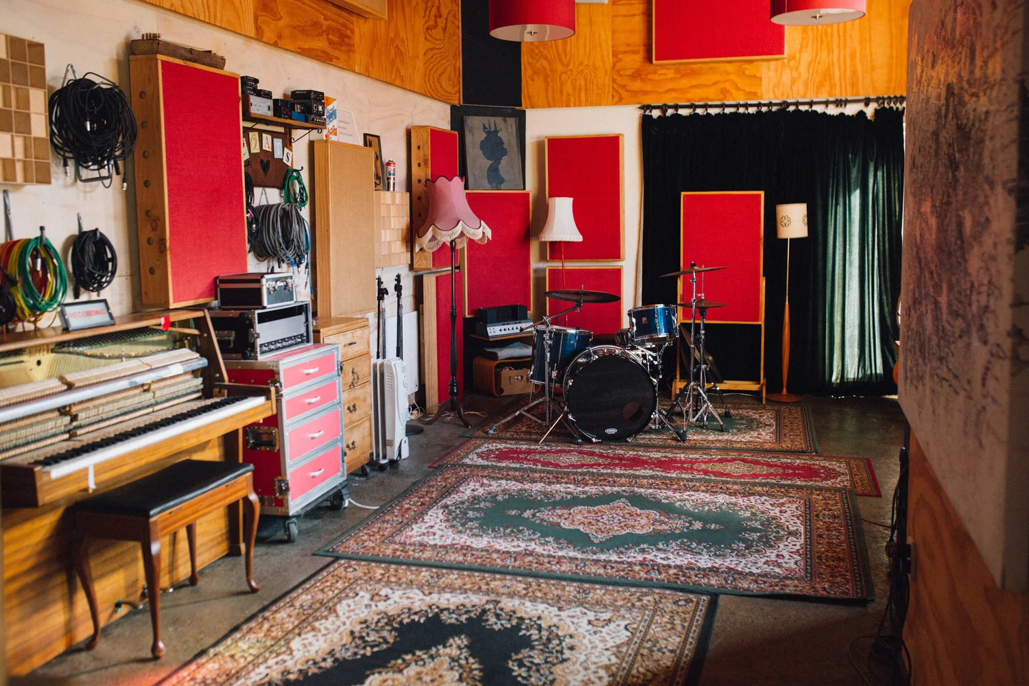 The main room of The Sitting Room studio, with piano, drums and red acoustic panels
