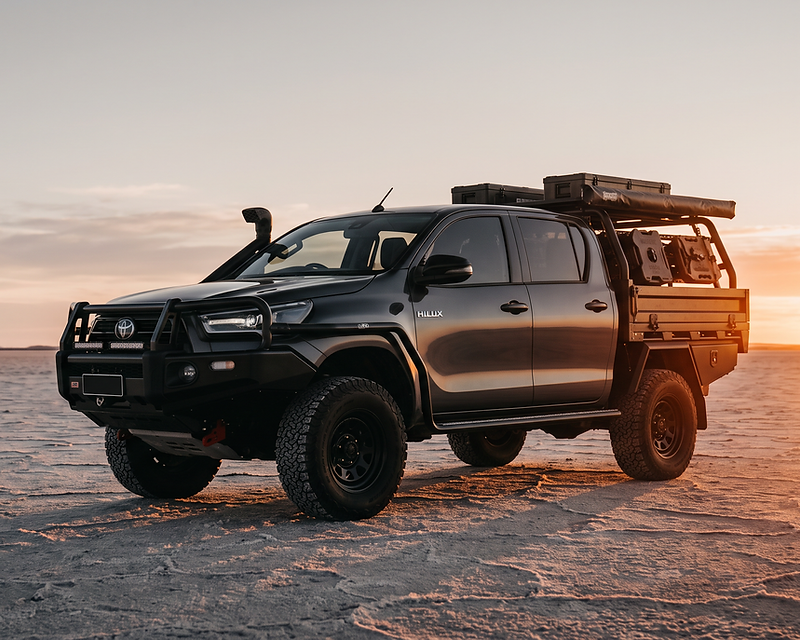 Modified N80 Toyota Hilux with bull bar, snorkel and tray rack on a salt flat at dusk