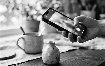 Black and white photo of a hand photographing a product with a smartphone