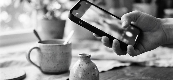 Black and white photo of a hand photographing a product with a smartphone
