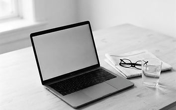 Black and white photo of a laptop on a minimal pale desk