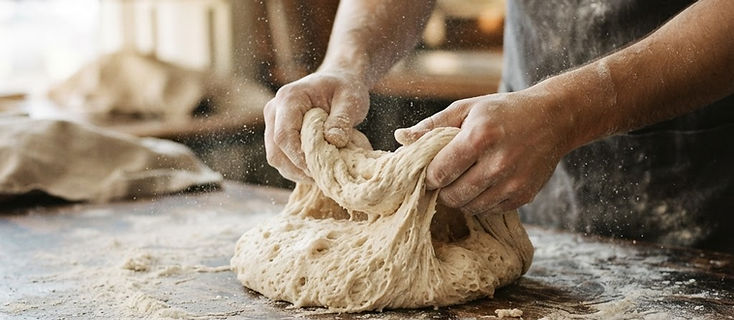 Mains pétrissant la pâte sur une table farinée