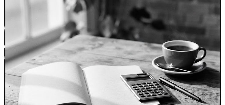 Black and white still life of a desk with a calculator and a notebook