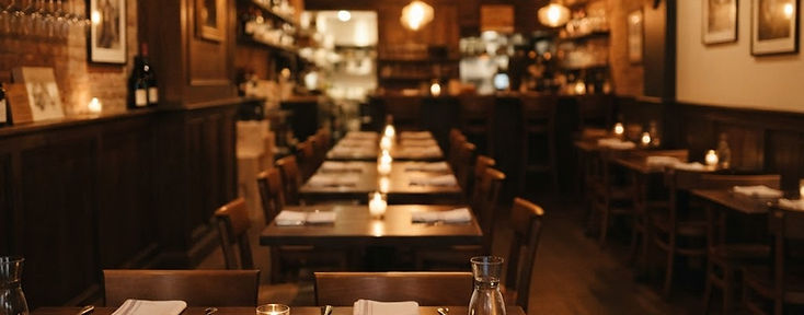 Salle du bistrot le soir, tables dressées et lumière chaude