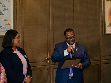 FDM executive holding a microphone and a framed certificate beside a delegate