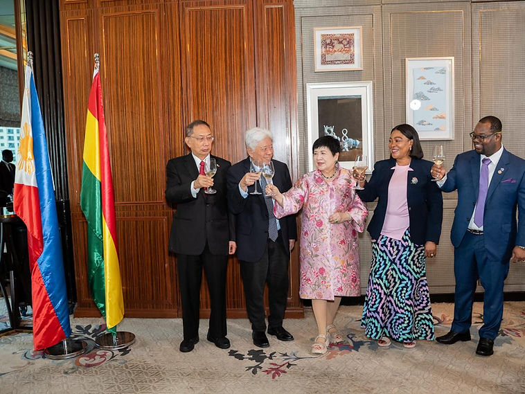 Five delegates raising glasses in a toast beneath the Philippine flag and a partner delegation's colours