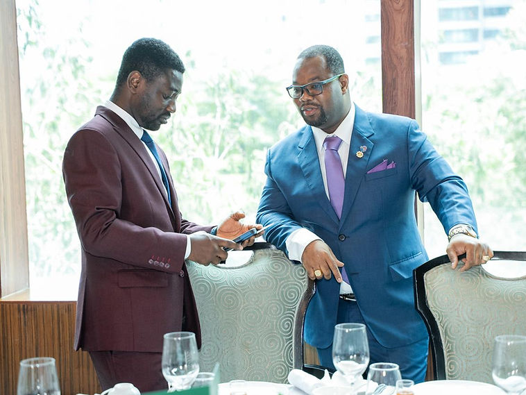 Two delegates in dark suits in conversation beside a laid dining table