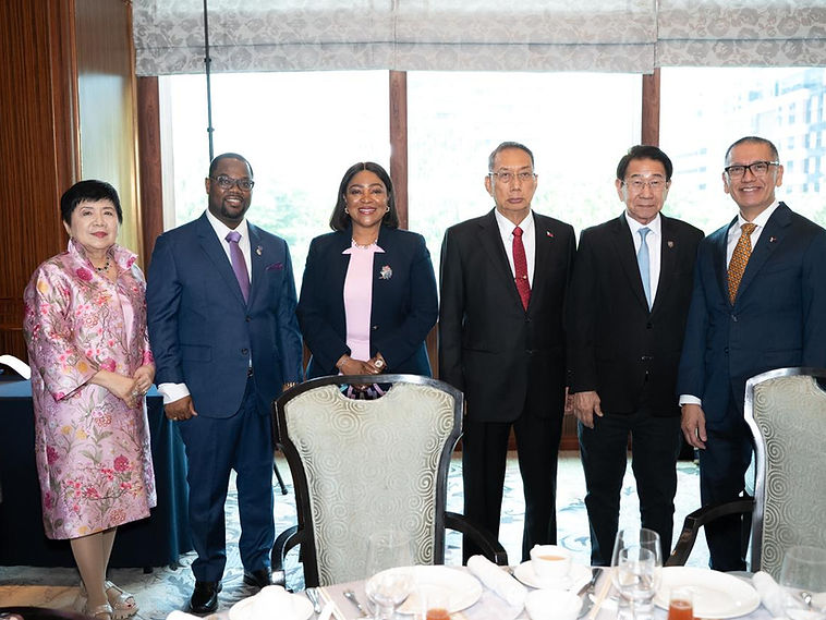 Six delegates posed for a group portrait around a dining table with a city view behind them