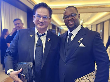 Two executives in dark suits standing together in a conference corridor