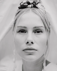 Black and white portrait of a blonde model in a braided updo with a knotted headpiece