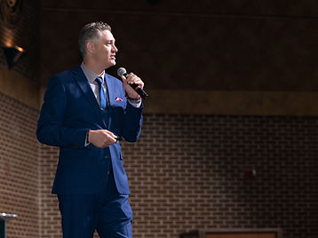 Joe Sallustio on stage against a brick wall, profile