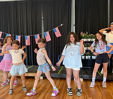 Showstoppers campers posing on stage with patriotic face paint and beaded necklaces