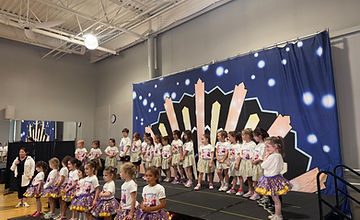 Full Team Zoey cast lined up on stage in gold and purple costumes