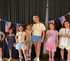 Showstoppers campers lined up on stage in front of a curtain with flag pennants