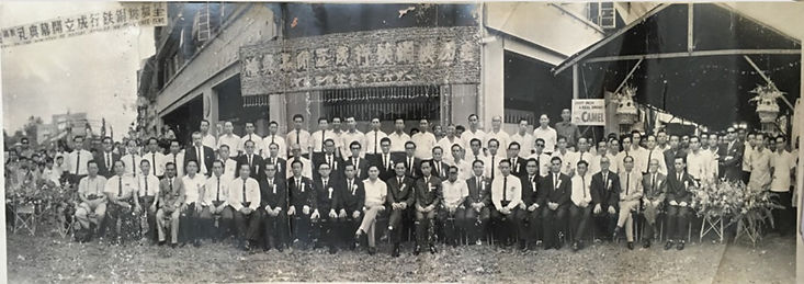 Archival photograph of a group gathered outside a traditional building bearing a 遠東行 banner