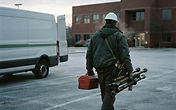 Fire protection technician staging sprinkler repair equipment from a service van at a commercial building at winter dawn in Dallas, Texas - USPA Nationwide Security