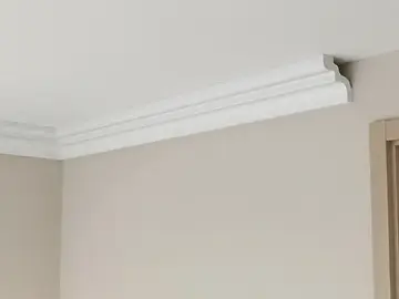 Moldura de teto branca em parede bege com perfil clássico de coroa