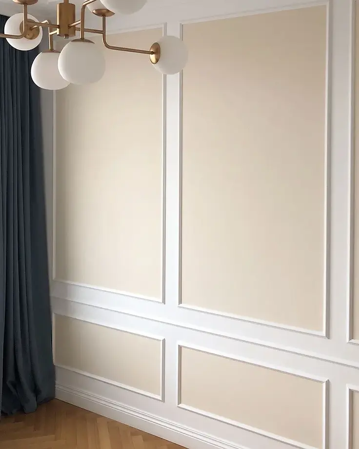 Boiserie branca com painéis em tom areia vestindo a parede de sala clara