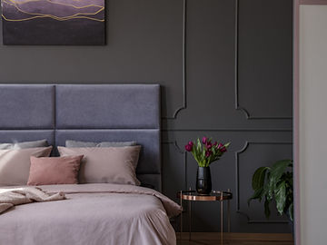 Boiserie aplicada em parede escura com cabeceira estofada e quadro decorativo