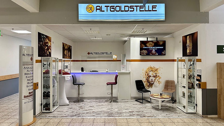 Die Altgoldstelle von vorn: Theke mit Barhockern, Vitrinen, Bildschirm und Warteecke unter dem beleuchteten Schild