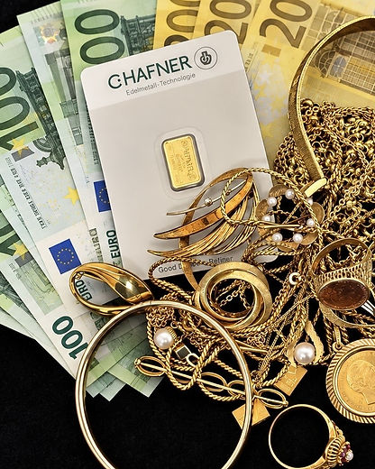Euro-Geldscheine neben einem Goldbarren in der Blisterkarte und Goldschmuck mit Ketten, Ringen und Perlen