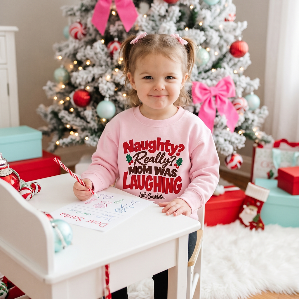 Toddler wearing a pink Little Sasshole Christmas sweatshirt while writing a letter to Santa.