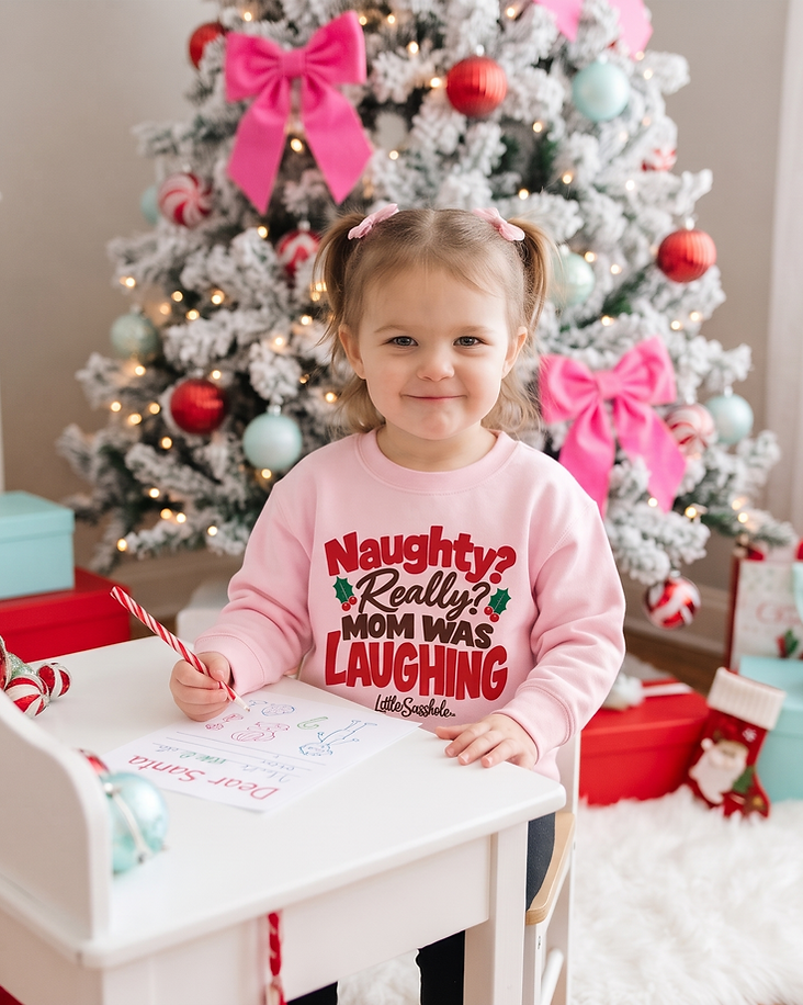 Toddler wearing a pink Little Sasshole Christmas sweatshirt while writing a letter to Santa.