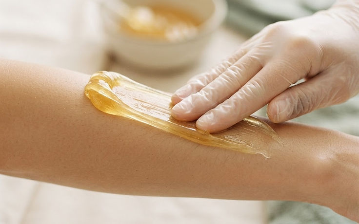 Gloved hand smoothing warm sugar paste along a forearm