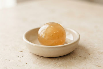 A ball of golden sugaring paste resting in a ceramic dish