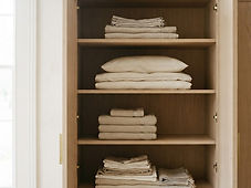 Neatly folded linen stacked on an oak wardrobe shelf
