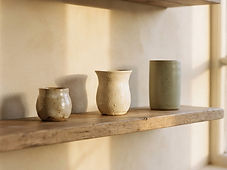 Three ceramic pieces spaced evenly on an open oak shelf