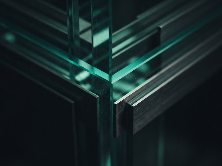 Macro detail of layered glass and steel catching a teal light, representing precise website design