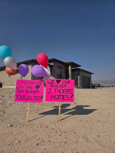 Balloons and handmade signs outside a home saying they love their builder, J Thomas Homes.