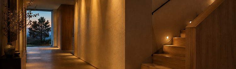 Warm layered lighting washing a hallway wall and staircase