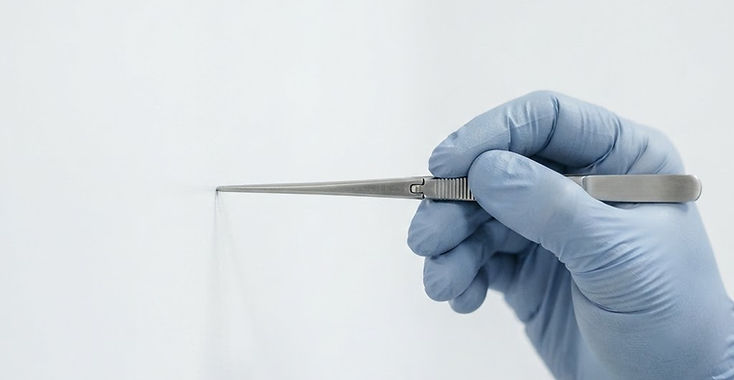 Lege med sterile hansker holder et kirurgisk instrument
