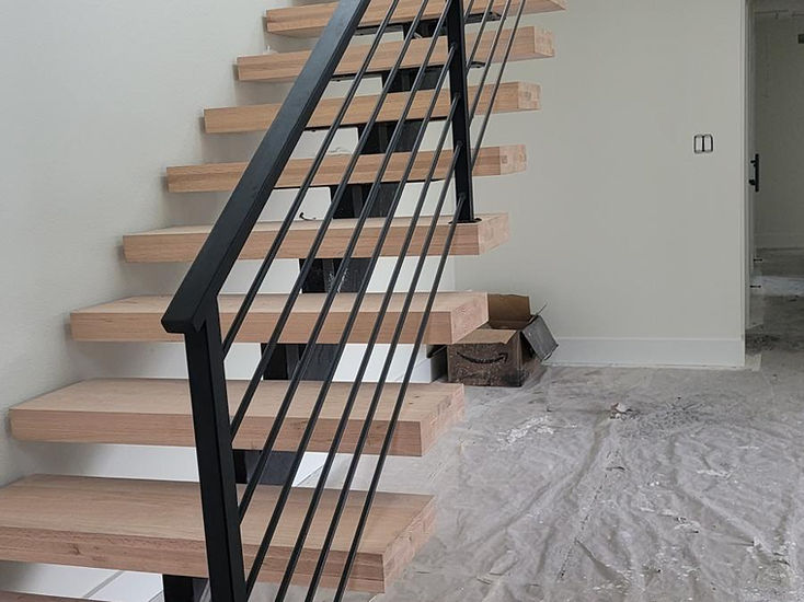 Escalera flotante de acero con viga central y barandal de barrotes, fabricada por RF Iron Works en Anna, TX