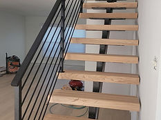 Open-riser stair with vertical bar steel railing. Stairs by RF Iron Works