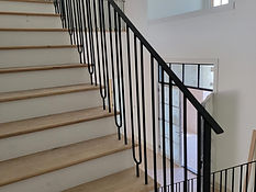 Wide staircase with loop-detail iron picket railing. Stairs by RF Iron Works