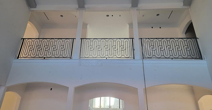 Barandal de hierro ornamental con volutas sobre una sala, fabricado por RF Iron Works