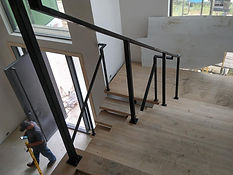 Black steel handrail anchored to a wood staircase. Railings by RF Iron Works