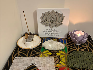 A lotus candle, crystals and burning sage on the Flower of Life cloth in the treatment room