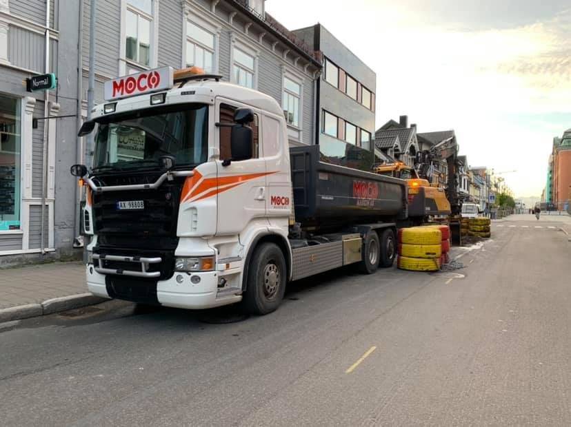 Hvit tippbil på lasteoppdrag i bymiljø