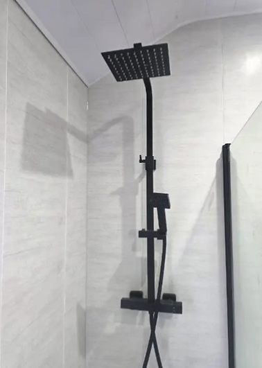 Matte black rain shower and thermostatic valve in a tiled shower enclosure
