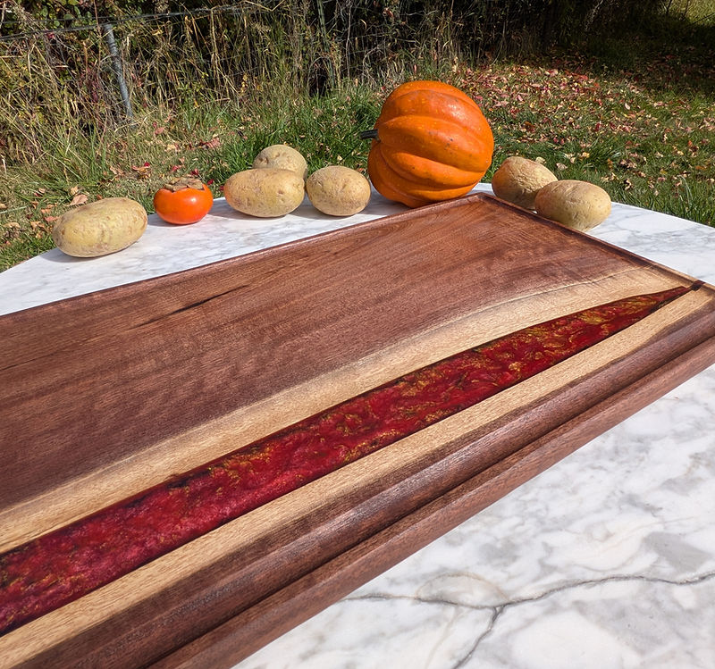 A walnut river board with deep red resin and gold leaf, on marble